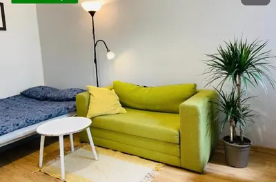 a green couch in a room with two plants at Sołtyka Apt in Kraków