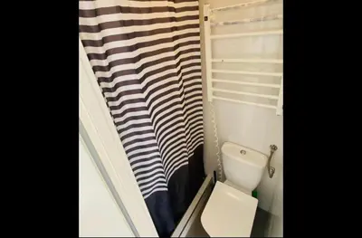 a bathroom with a toilet and a striped shower curtain at Sołtyka Apt in Kraków
