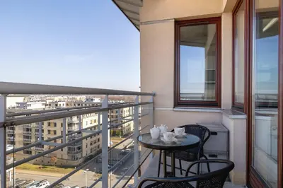 a balcony with a table and chairs and a view of a city at Przestronny i Przytulny Apartament w Krakowie z Parkingiem i Balkonem by Noclegi Renters in Kraków