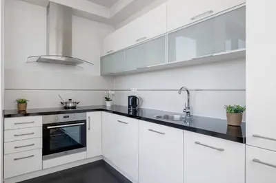 a white kitchen with white cabinets and a sink at Przestronny i Przytulny Apartament w Krakowie z Parkingiem i Balkonem by Noclegi Renters in Kraków