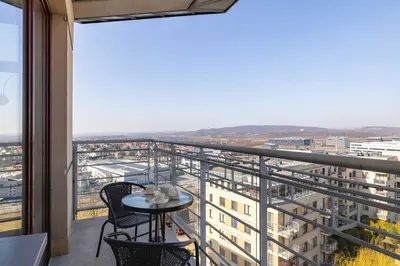 a balcony with a table and chairs and a view at Przestronny i Przytulny Apartament w Krakowie z Parkingiem i Balkonem by Noclegi Renters in Kraków