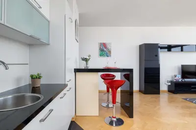 a red stool sits in the middle of a kitchen at Przestronny i Przytulny Apartament w Krakowie z Parkingiem i Balkonem by Noclegi Renters in Kraków