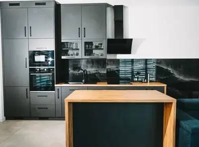 a kitchen with white cabinets and a wooden table at Loft House Rabka dom na wyłączność z jacuzzi SKI&SPA in Rabka