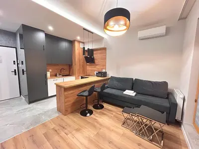 a living room with a couch and a kitchen at ApartmentPrestige Premium in Kraków