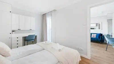 a white bedroom with a bed and a desk at Riva Verona, Sun & Snow in Kraków