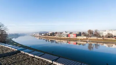 a view of a river with buildings in the background at Riva Verona, Sun & Snow in Kraków