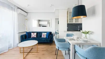 a living room with a blue couch and a table at Riva Verona, Sun & Snow in Kraków
