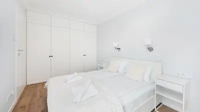 a white bedroom with a white bed and white cabinets at Riva Verona, Sun & Snow in Kraków