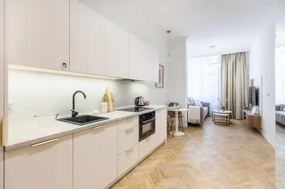 a kitchen with white cabinets and a living room at Apartament Długa 24 in Kraków