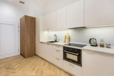 a kitchen with white cabinets and a wooden floor at Apartament Długa 24 in Kraków