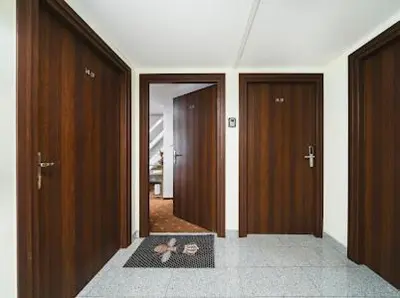 a hallway with three wooden doors in a room at Queen Bee Apartments Krakow Old Town in Kraków