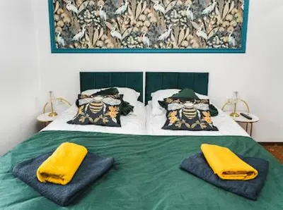 a bedroom with a green bed with yellow towels on it at Queen Bee Apartments Krakow Old Town in Kraków