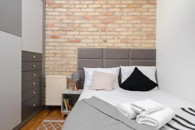 a bedroom with a bed with a brick wall at Park Krakowski Loft Apartment by BookingHost in Kraków