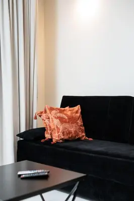 a black couch with an orange pillow and a table at City of the Kings-Copper Nest in Kraków
