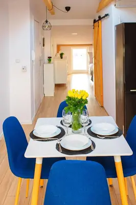 a dining room table with blue chairs and a kitchen at Scandi-Style Escape in Krakow in Kraków
