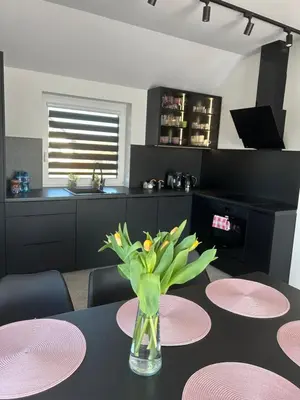 a table with pink plates and a vase with flowers on it at DS Apartamenty Zator in Zator