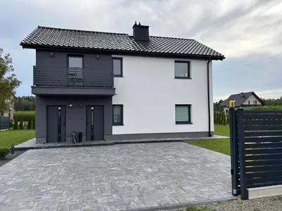 a white house with a black roof and a driveway at DS Apartamenty Zator in Zator