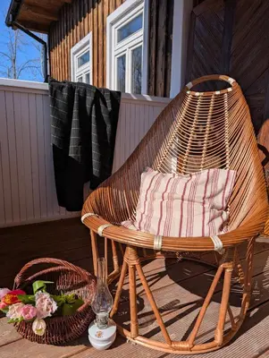 a wicker chair on a porch with a basket of flowers at Płachtówka in Słupia