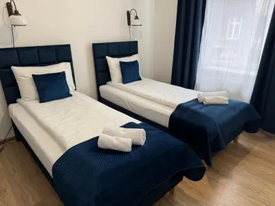 two beds in a room with towels on them at Apartments Iris-Topolowa in Kraków
