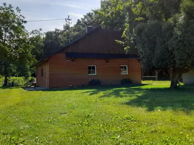 a barn in a field with a grass yard at Domek Na Skraju Lasu in Wola Batorska