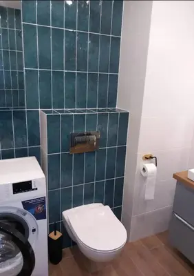 a bathroom with a toilet and a green tiled wall at Apartament Salwator in Kraków