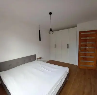a bedroom with a white bed and a wooden floor at Apartament Salwator in Kraków