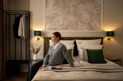 a woman sitting on top of a bed at OLD TOWN Charm & Chic by Downtown Apartments in Kraków
