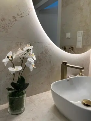 a bathroom with a sink and a vase with white flowers at Tropical Novum Apartment - Krakow Old Town in Kraków
