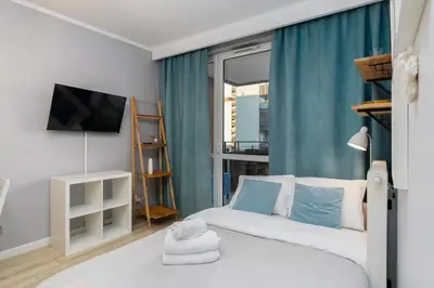 a bedroom with a bed with blue curtains and a tv at Osiedle Avia Cosy Apartment by BookingHost in Kraków