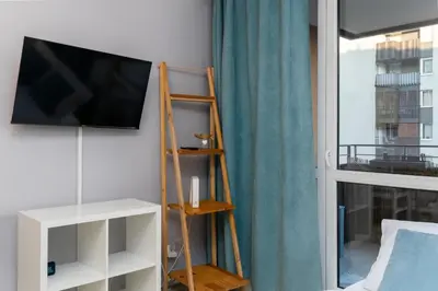a room with a tv on a wall next to a window at Osiedle Avia Cosy Apartment by BookingHost in Kraków
