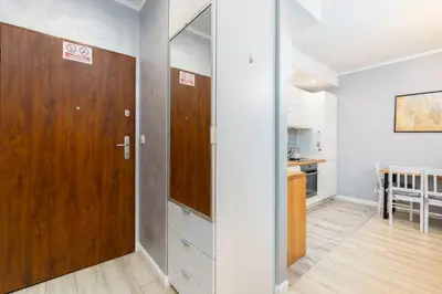a hallway with a wooden door and a kitchen at Osiedle Avia Cosy Apartment by BookingHost in Kraków