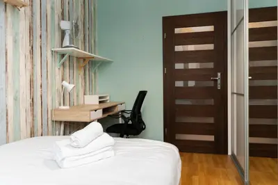 a bedroom with a bed and a desk with towels at Osiedle Avia Cosy Apartment by BookingHost in Kraków