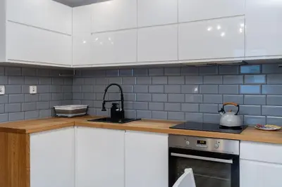 a kitchen with white cabinets and a tea kettle at Osiedle Avia Cosy Apartment by BookingHost in Kraków
