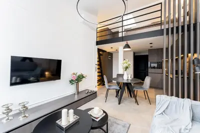 a living room with a table and chairs and a tv at Wielopole Top Floor Apartments by Hostly in Kraków
