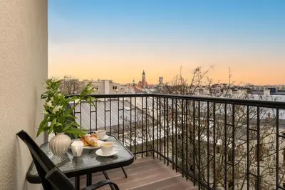 a table on a balcony with a view of the city at Wielopole Top Floor Apartments by Hostly in Kraków
