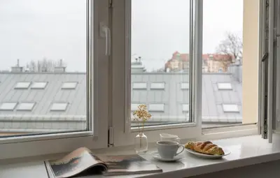 a table with a plate of croissants and cups and a window at Wielopole Top Floor Apartments by Hostly in Kraków