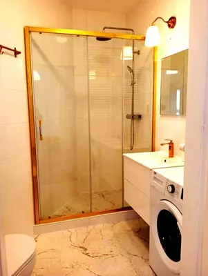a bathroom with a shower and a washing machine at M Apartment in Kraków