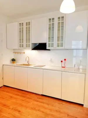 a white kitchen with white cabinets and a wooden floor at M Apartment in Kraków