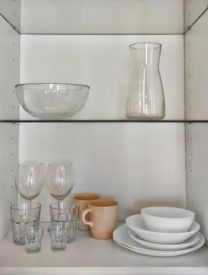 a shelf with glasses and plates and cups on it at M Apartment in Kraków