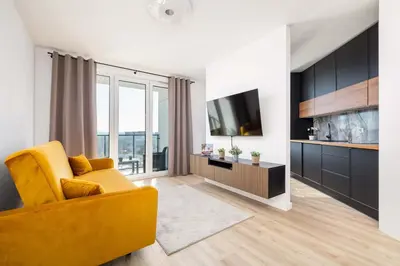 a living room with a yellow couch and a television at Elegant Apartment with Parking near Tauron Arena Kraków by Noclegi Renters in Kraków