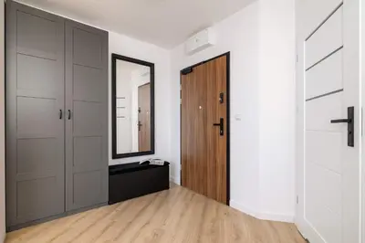 a hallway with a wooden door and a mirror at Elegant Apartment with Parking near Tauron Arena Kraków by Noclegi Renters in Kraków