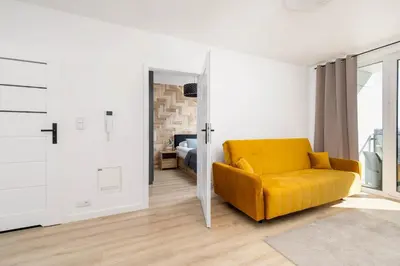 a yellow couch in a room with a bedroom at Elegant Apartment with Parking near Tauron Arena Kraków by Noclegi Renters in Kraków