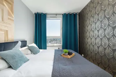 a bedroom with a bed with blue curtains and a window at Elegant Apartment with Parking near Tauron Arena Kraków by Noclegi Renters in Kraków