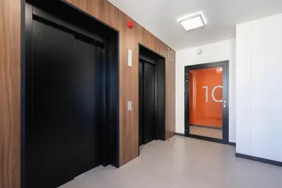 a hallway with two black doors in a building at Elegant Apartment with Parking near Tauron Arena Kraków by Noclegi Renters in Kraków
