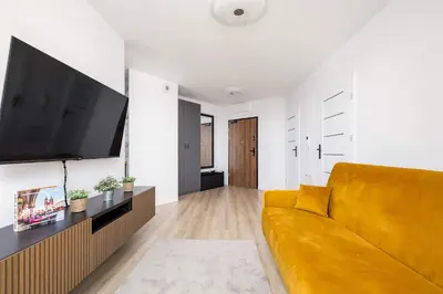 a living room with a yellow couch and a flat screen tv at Elegant Apartment with Parking near Tauron Arena Kraków by Noclegi Renters in Kraków