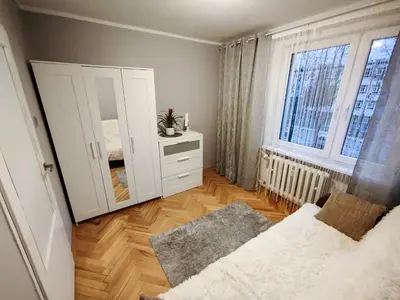 a bedroom with a white cabinet and a mirror at New Fifth Apartament in Kraków