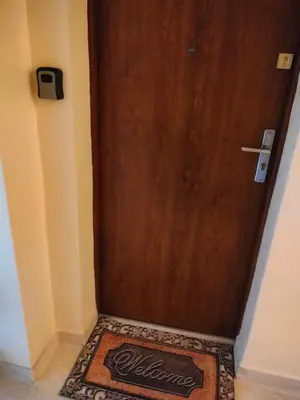 a wooden door with a welcome mat in front of it at New Fifth Apartament in Kraków