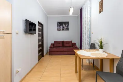 a living room with a table and a red couch at Wawel neighborhood in Kraków