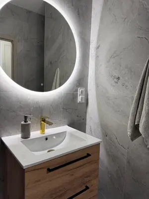 a bathroom with a white sink and a mirror at Apartamenty przy Malborskiej in Kraków