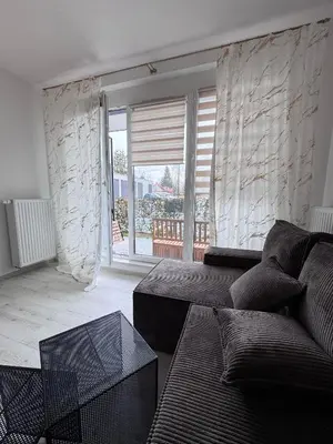 a living room with a couch and a large window at Apartamenty przy Malborskiej in Kraków